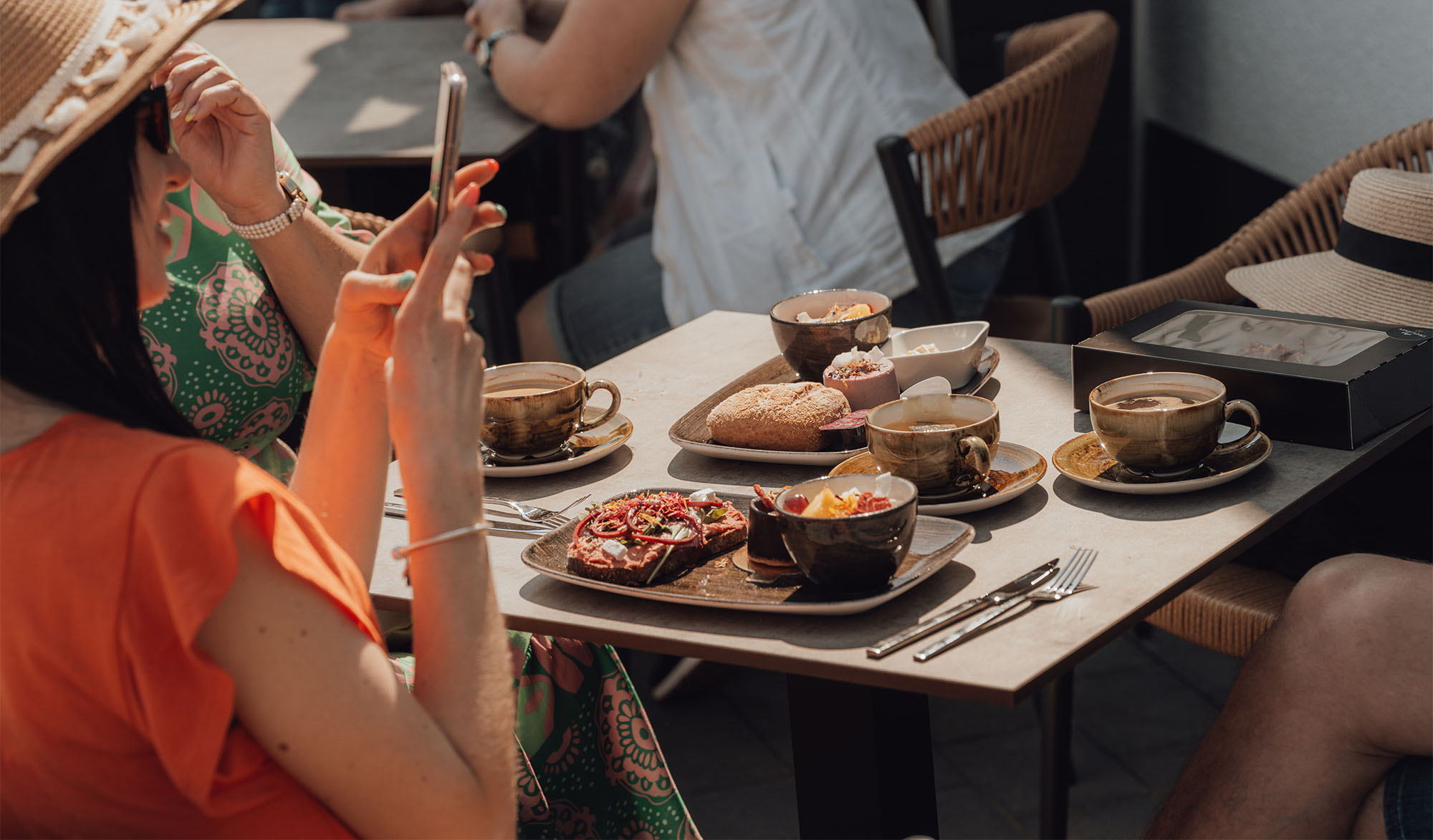 Frau im Café macht Foto vom Essen mit ihrem Smartphone